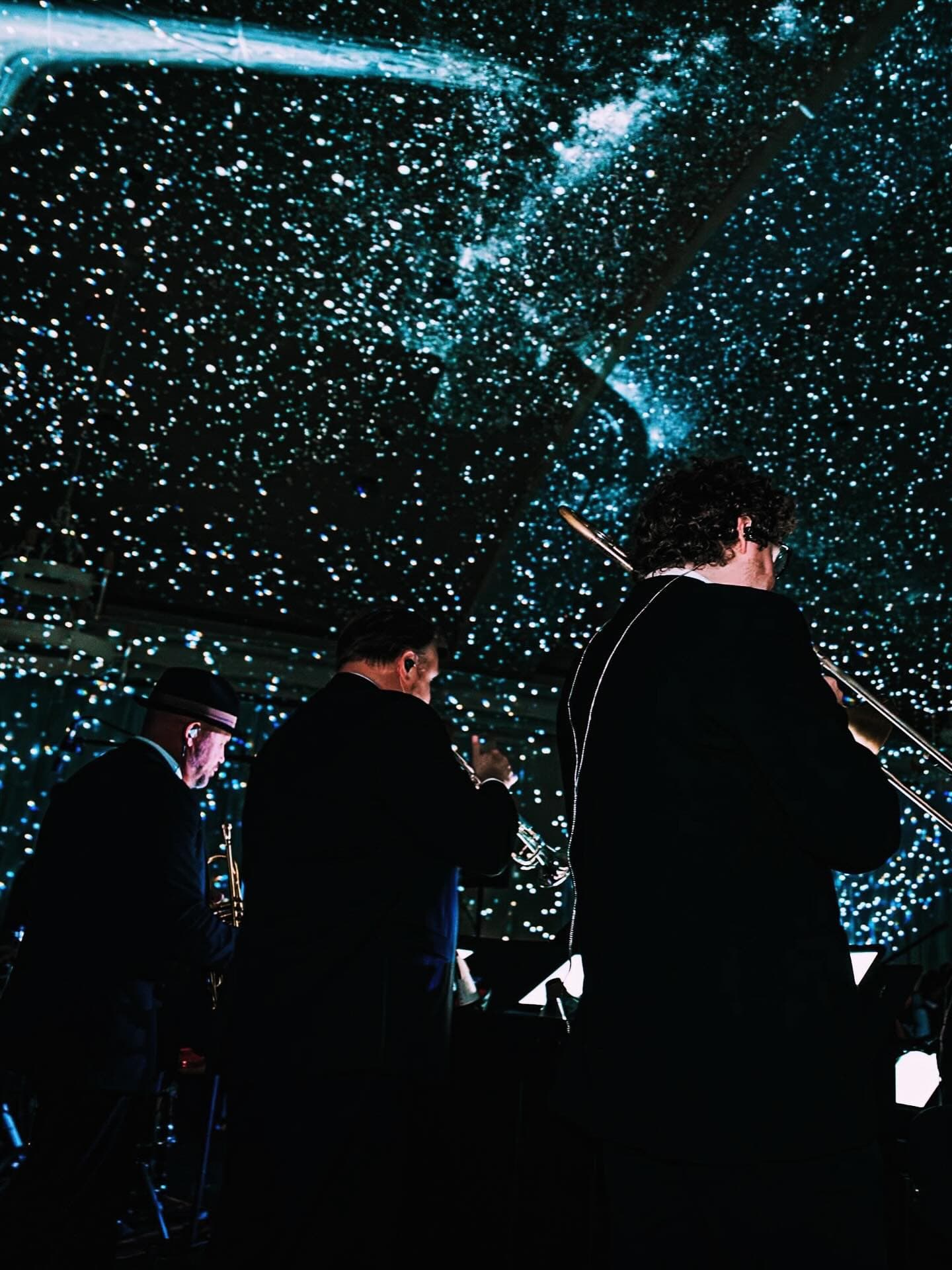 The horn section seen from behind, facing a sky of stars
